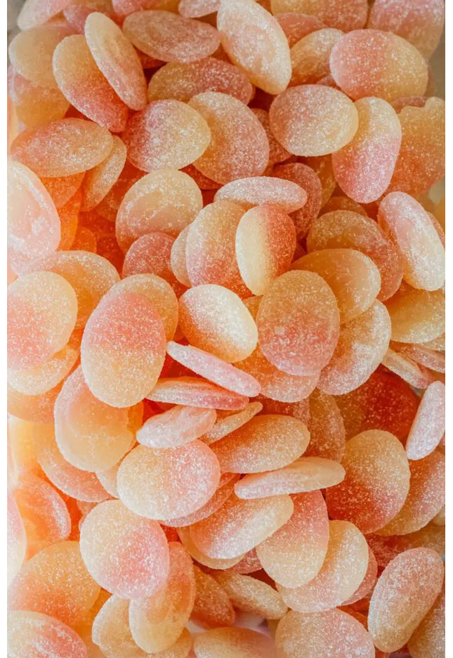 Close-up of peach-colored gummy candies covered in sugar.