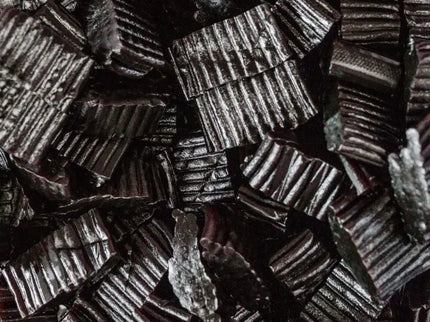 Close-up of black licorice candies arranged tightly together.