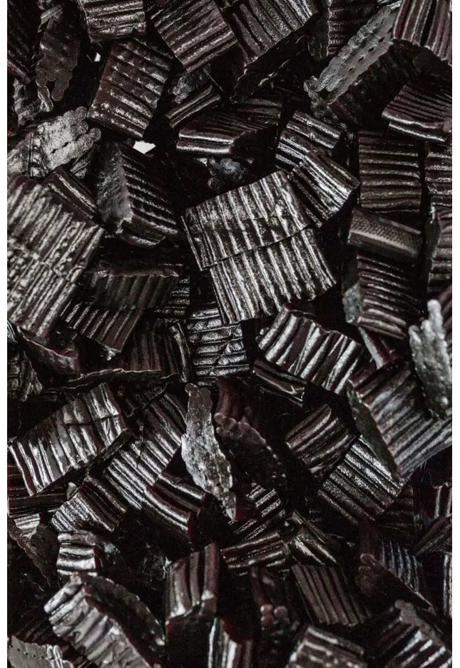 Close-up of black licorice candies arranged tightly together.