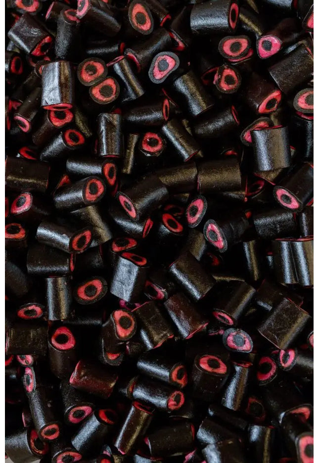 Close-up of black cylindrical beads with red centers scattered densely.