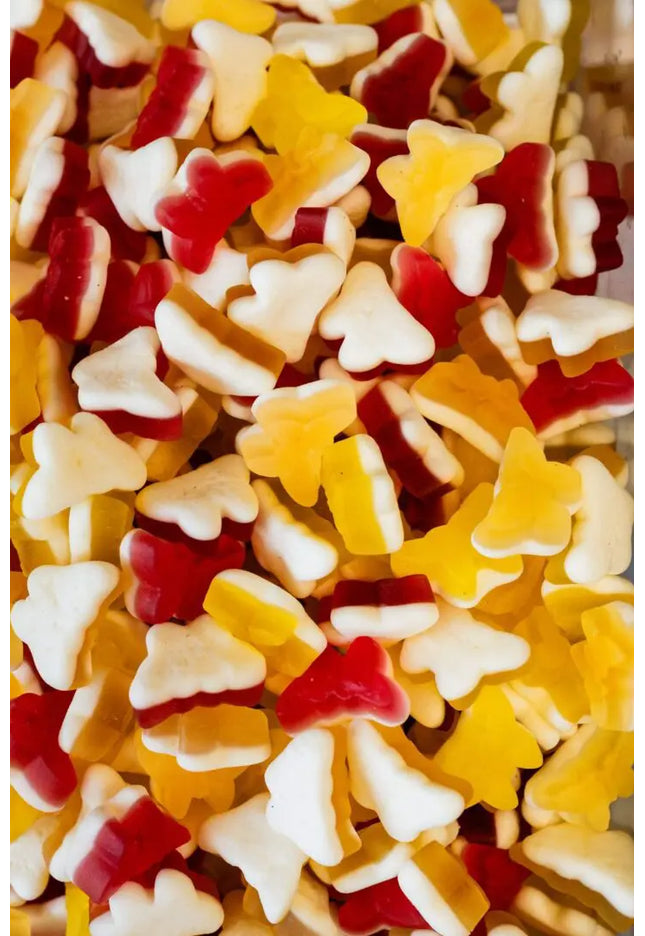 Colorful gummy candies shaped like Christmas trees in red, yellow, and white.