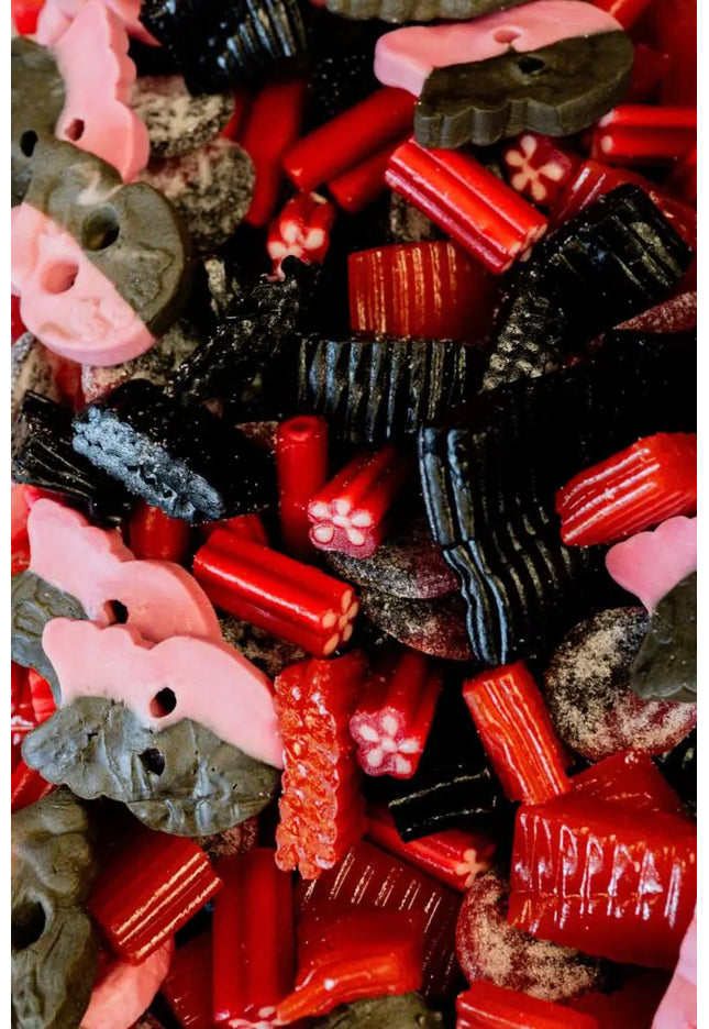 A close-up of mixed black and red licorice candies with pink marshmallow pieces.