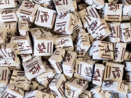 A pile of individually wrapped candies with brown and white packaging.