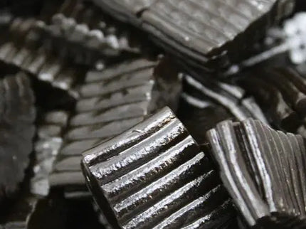 Close-up of black licorice candy pieces with ridged texture.