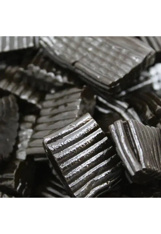 Close-up of black licorice candy pieces with ridged texture.