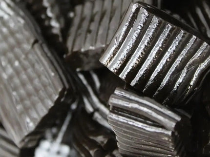 Close-up of black licorice candy pieces with ridged texture.