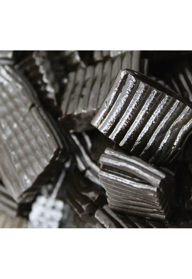 Close-up of black licorice candy pieces with ridged texture.