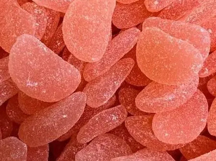Close-up of numerous pink sugar-coated Sour Watermelon gummy candies piled together.